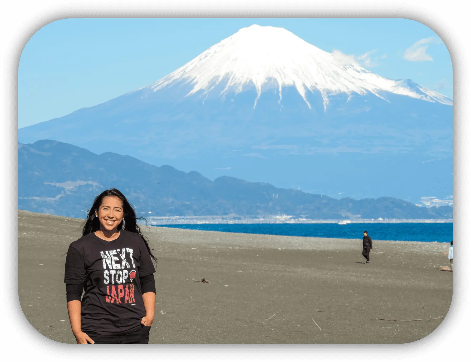 Viajante em uma praia, com o Monte Fuji coberto de neve ao fundo