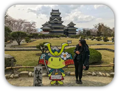 Viajante e painel de um personagem samurai nos jardins do Castelo de Matsumoto